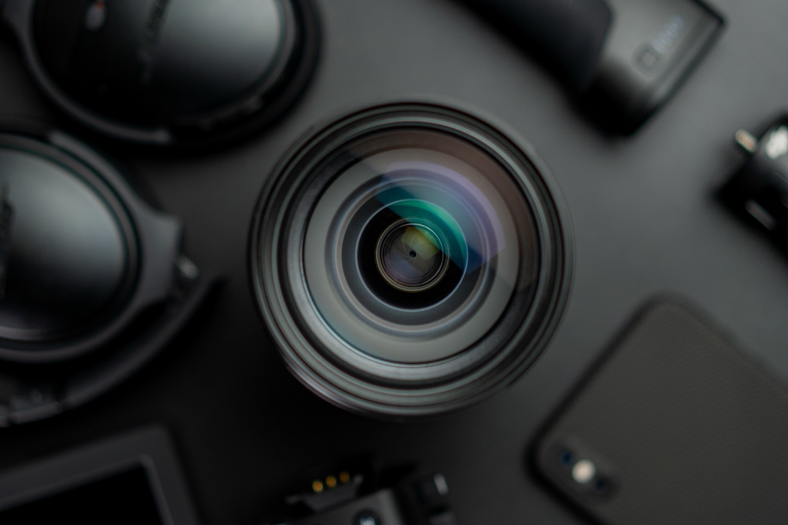 A camera lens seen head on, surrounded by photography gear