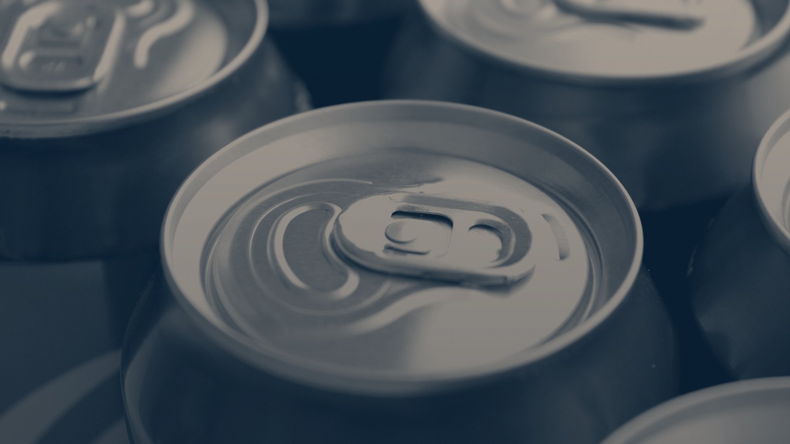 Close on the ring pull of a red aluminium cola can, rows of identical cans running out of focus behind it, navy duotone.