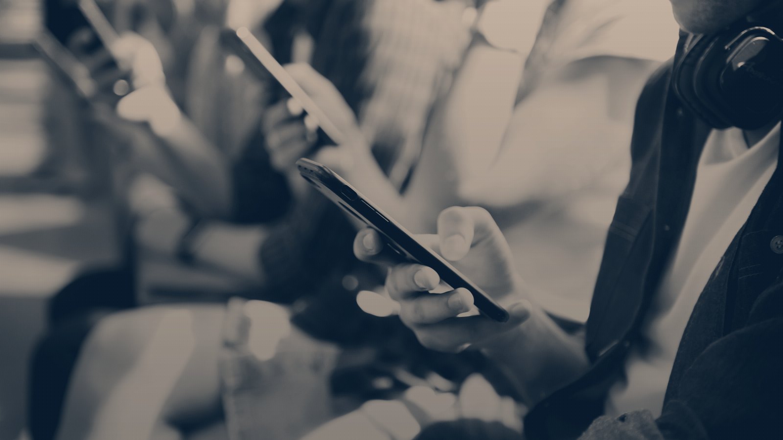 A row of people sitting side by side, each one looking down at their phone
